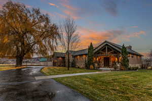 View of front of home with a yard, stone siding, asphalt driveway, and a chimney