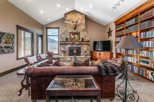 Carpeted living room with a fireplace and vaulted ceiling