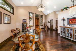 Dining area with dark wood-type flooring, a chandelier, recessed lighting, and high vaulted ceiling