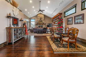 Dining room featuring a fireplace, dark wood-style flooring, a ceiling fan, high vaulted ceiling, and recessed lighting