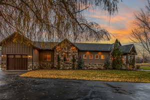 Chalet / cabin featuring an attached garage, stone siding, a front yard, and driveway