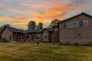 Back of property with board and batten siding, a yard, a patio area, and a chimney