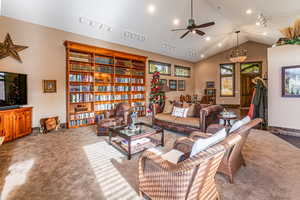 Living area with lofted ceiling, a ceiling fan, and track lighting