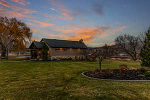 View of front of house with a front yard, a chimney, and stone siding