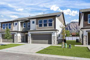 View of front of property featuring stone siding, concrete driveway, an attached garage, board and batten siding, and a mountain view