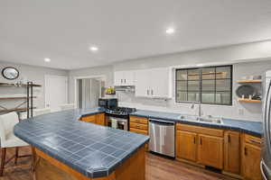 Kitchen featuring appliances with stainless steel finishes, dark wood-style floors, open shelves, tile counters, and recessed lighting