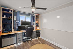 Office space with dark wood-style flooring, ornamental molding, and a ceiling fan