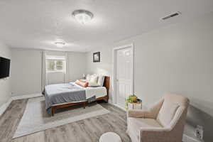 Bedroom with a textured ceiling and wood finished floors
