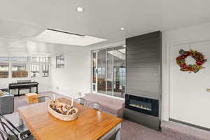 Dining room featuring light colored carpet, a fireplace, and recessed lighting