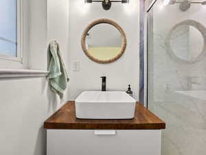 Bathroom featuring vanity and a marble finish shower
