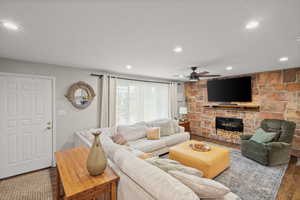 Living area featuring wood finished floors, a stone fireplace, recessed lighting, and ceiling fan