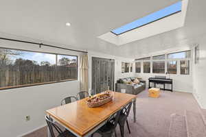 Dining area with carpet, a skylight, and lofted ceiling