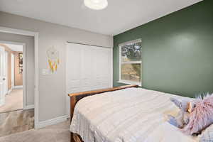 Carpeted bedroom featuring a closet and wood finished floors