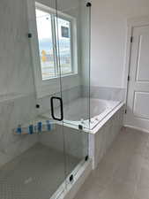 Bathroom with a marble finish shower, tile patterned floors, and a bath