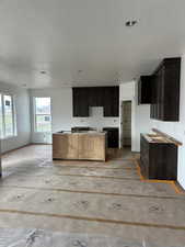 Kitchen with a kitchen island, a textured ceiling, and dark brown cabinets