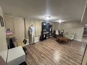 Living area featuring a desk, a textured ceiling, and a decorative wall