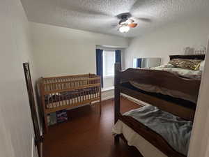 Bedroom featuring dark wood finished floors, a ceiling fan, and a textured ceiling