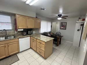 Kitchen with dishwasher, a peninsula, light stone countertops, and light tile patterned flooring