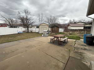 Fenced backyard with a storage unit, a patio area, outdoor dining space, and area for grilling