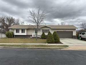 Ranch-style home featuring driveway, an attached garage, and roof with shingles