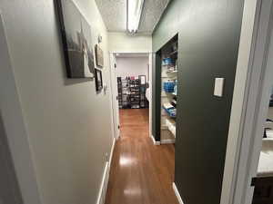 Corridor with wood-style floors and a textured ceiling
