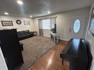 Foyer entrance featuring recessed lighting, a textured ceiling, wood finished floors, and carpet floors