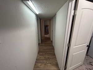 Hall featuring a textured ceiling and wood finished floors
