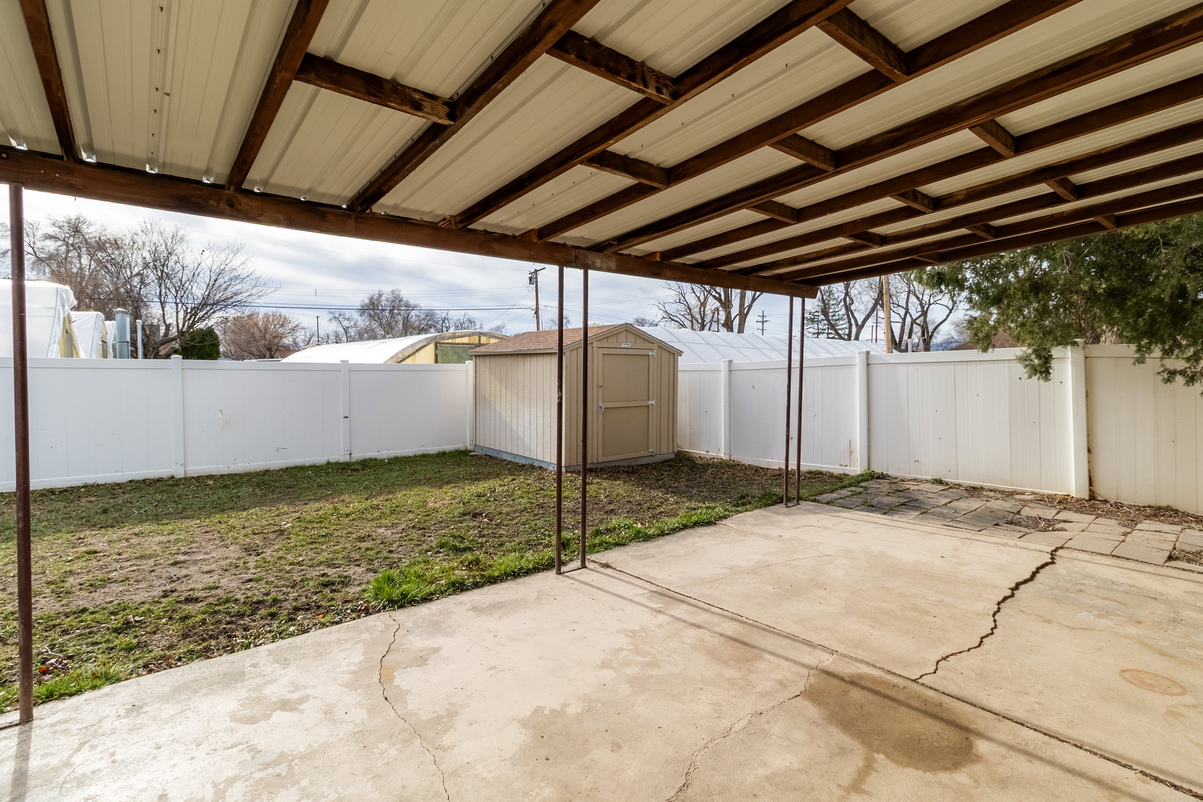 Fenced backyard featuring a storage shed and a patio area