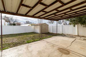 Fenced backyard featuring a storage shed and a patio area