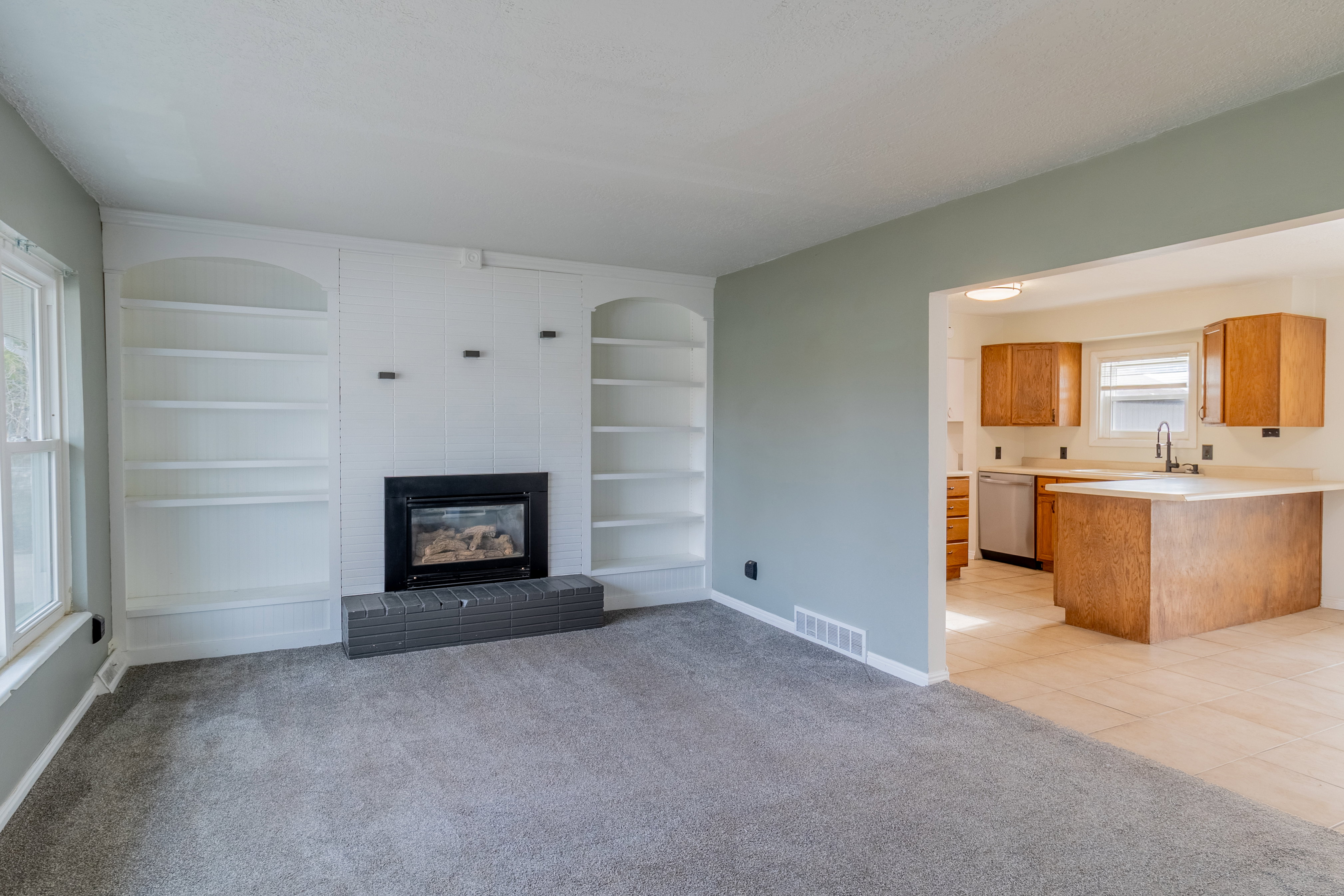 Unfurnished living room featuring built in features, a large fireplace, and light carpet