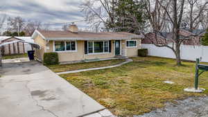View of front of house with stucco siding, a chimney, driveway, and a carport