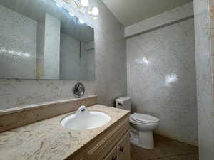Bathroom with light tile patterned floors, vanity, and wallpapered walls