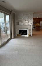 Unfurnished living room featuring light carpet, a premium fireplace, and ornamental molding