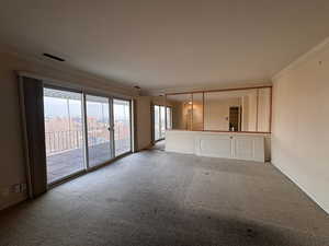 Unfurnished living room featuring crown molding and carpet floors