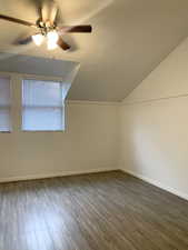 Bonus room featuring lofted ceiling, dark wood finished floors, a ceiling fan, and a textured ceiling
