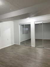 Unfurnished bedroom with dark wood-style flooring, two closets, and a textured ceiling