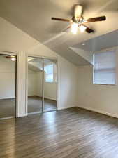 Unfurnished bedroom with lofted ceiling, two closets, dark wood finished floors, and ceiling fan
