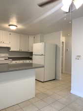 Kitchen featuring dark countertops, white appliances, white cabinetry, a textured ceiling, and under cabinet range hood