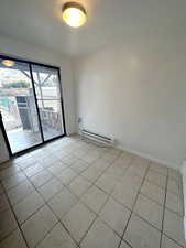 Tiled empty room with a textured ceiling and baseboard heating