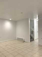 Spare room with stairs, baseboard heating, light tile patterned flooring, and recessed lighting