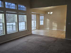 Carpeted empty room featuring hanging lights and tile patterned flooring