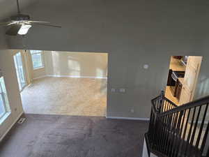 Unfurnished living room with a ceiling fan, light carpet, lofted ceiling, and light tile patterned flooring