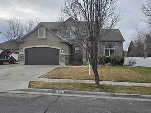 Traditional-style home with stone siding, driveway, stucco siding, and a garage