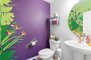 Half bathroom featuring baseboards and toilet