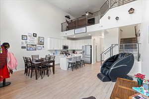 Dining room with light wood-style flooring, a towering ceiling, and stairs