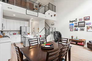 Dining area featuring stairs, a towering ceiling, light wood finished floors, and recessed lighting
