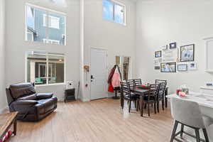Dining area with light wood finished floors and a towering ceiling