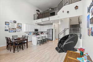 Living room with light wood-style floors, stairs, and a towering ceiling