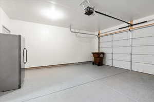 Garage with freestanding refrigerator and a garage door opener