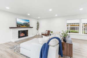 Living room with a fireplace, light wood finished floors, and recessed lighting
